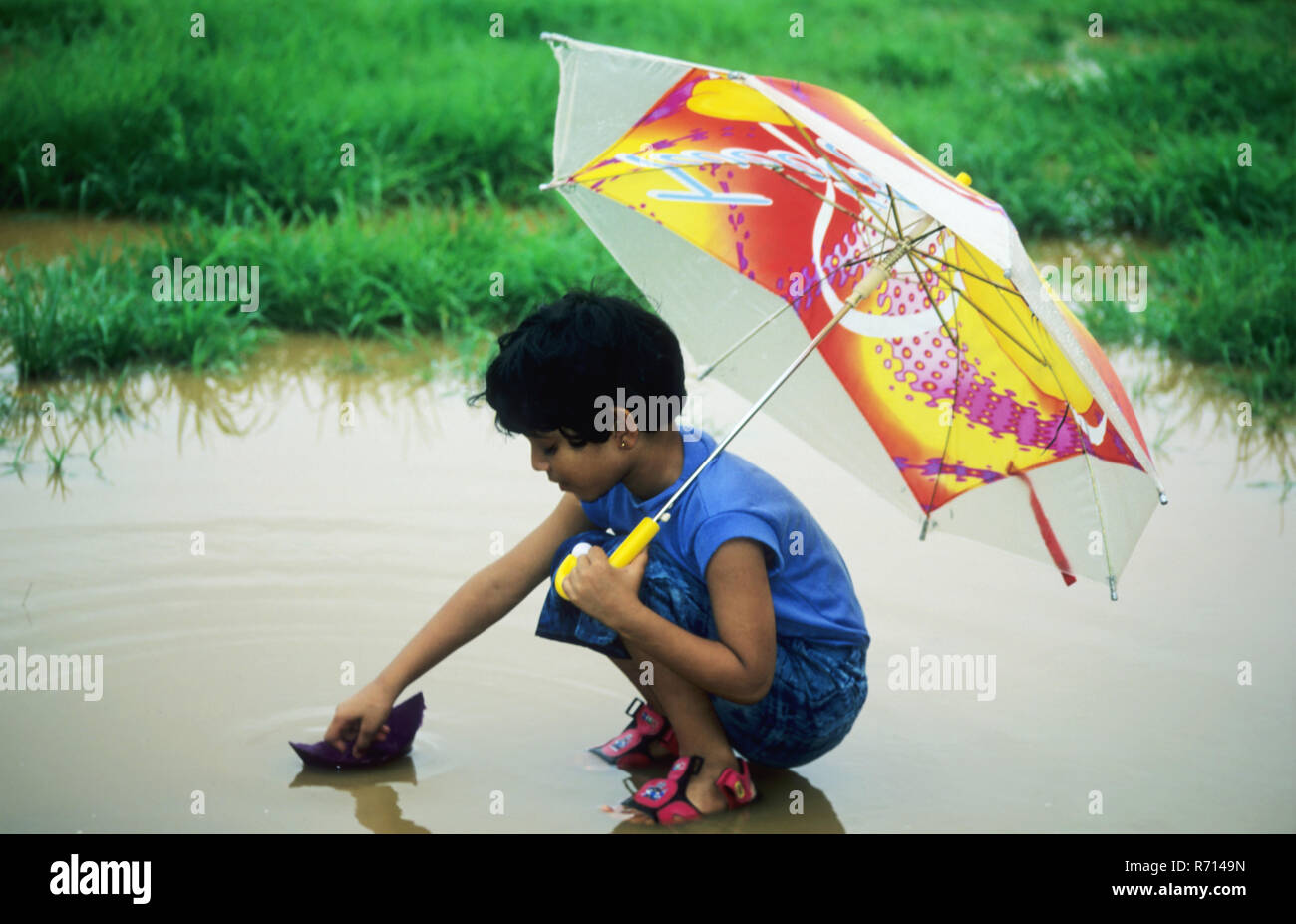 Mädchen Segeln Papier Boot im Regenwasser, dadar, Bombay Mumbai, Maharashtra, Indien Stockfoto