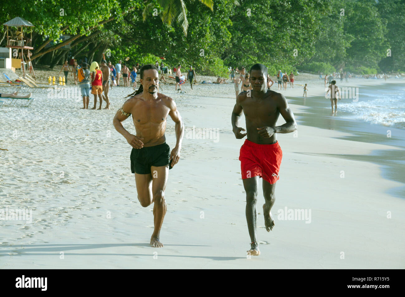 Zwei Creole Männer auf einem morgens joggen am Strand entlang, Mahe Island, Seychellen Stockfoto