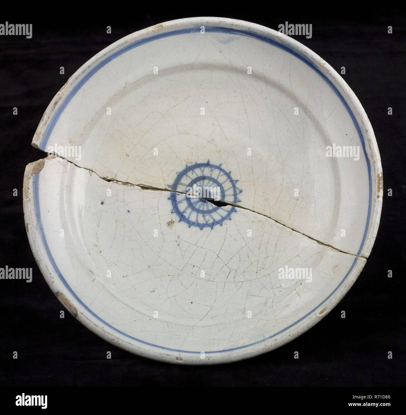 Fayence Schild auf dem stand, blau Dekor, kleine Rosette in der Mitte, blaue Verkleidung am Rande, Platte Geschirr halter Boden Keramik Steingut Glasur Glasur finden Zinn, von Hand gedreht gebackene dekoriert glasiert gebratene Fayence Platte auf kleinen ständigen Oberfläche stark gekrümmte Schale nur Kante am oberen flachen Schulter auf den Übergang auf die Flagge. Blaues Dekor auf weißem Fond. Kleine Rosette in der Mitte der Spiegel und blauen Streifen auf die Flagge. In der Roehre gekocht. Misbaksel Gericht ist in zwei während der zweiten Mal backen Archäologie Stadt Dreieck Rotterdam Rathaus indigenen Töpferei Kunsthandwerk Keramik Boden Entdeckung gebrochen: Pro Stockfoto