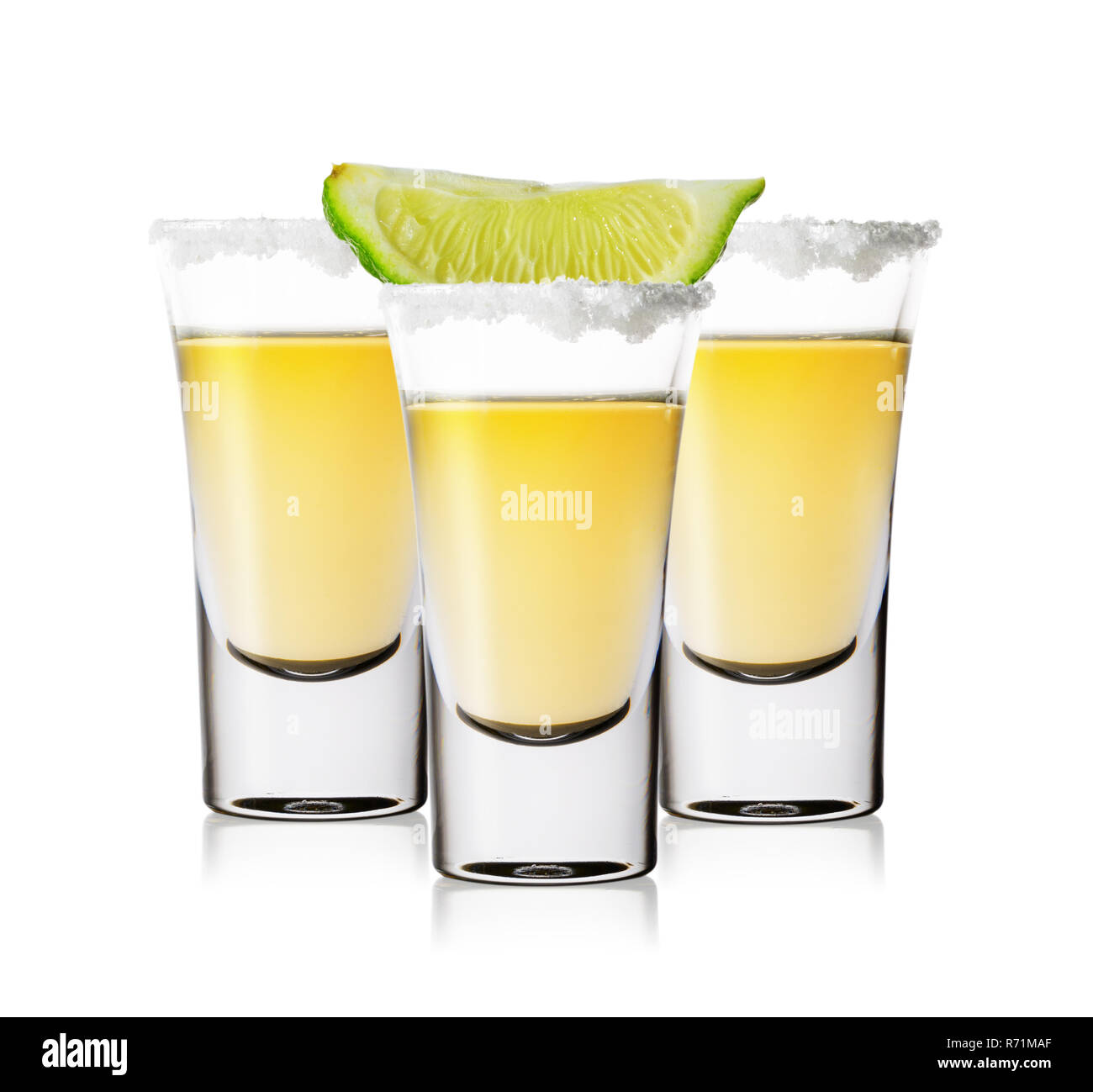Drei Gläser golden Tequila mit Salz und Kalk auf weißem Hintergrund. Traditionelle mexikanische Starke alkoholische Getränk. Stockfoto
