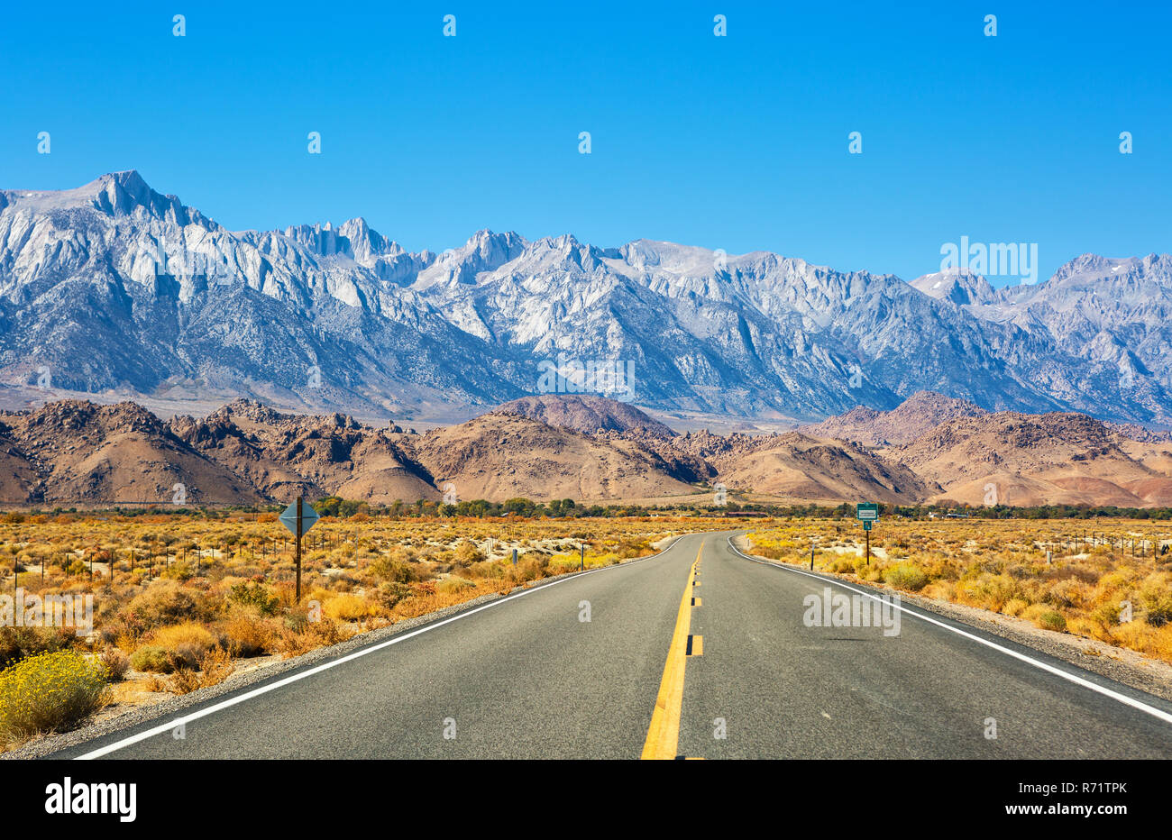 Leere Straße in der Nähe von Lone Pine mit Felsen der Alabama Hills und der Sierra Nevada im Hintergrund, Inyo County, Kalifornien, USA. Stockfoto