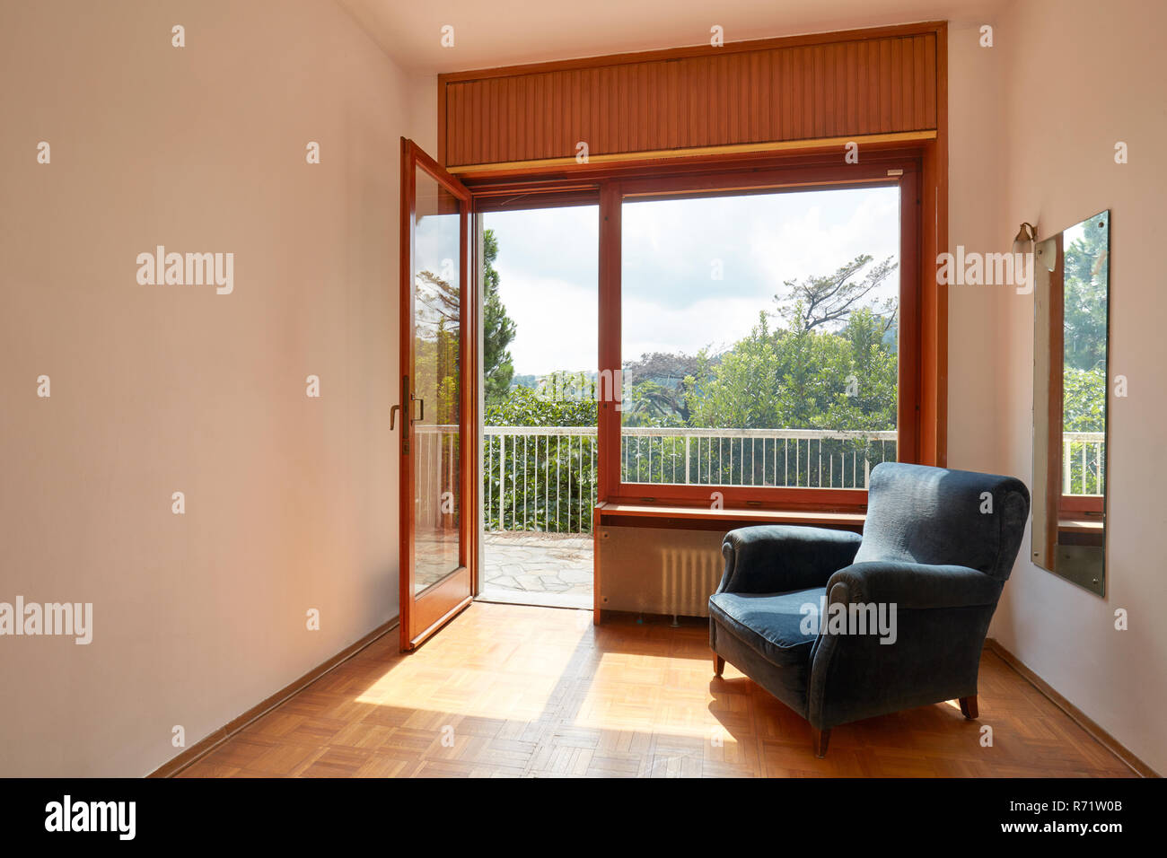 Sonniges Zimmer mit Terrasse und Blue Velvet Sessel im Landhaus Stockfoto