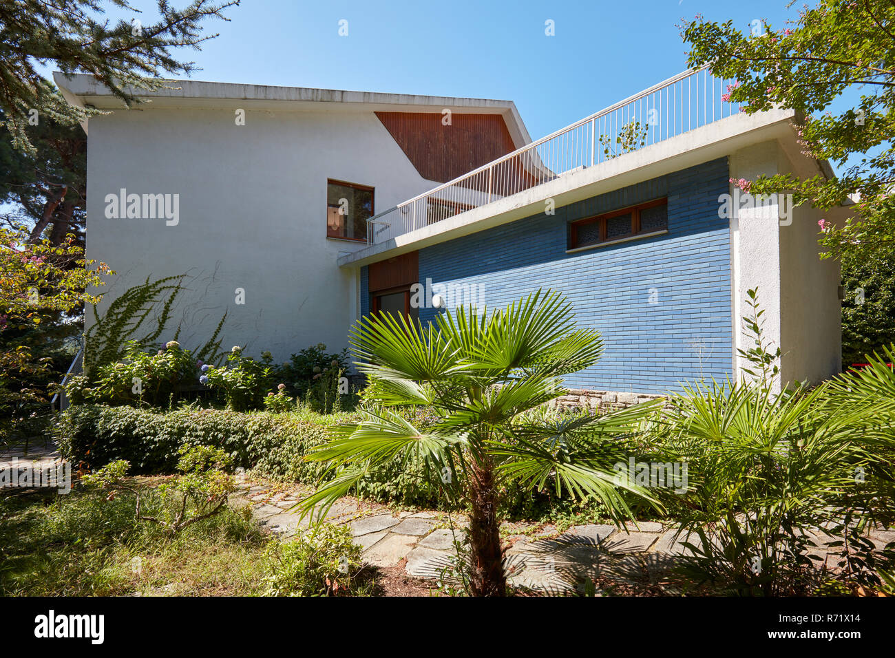 Villa mit Garten, Pfad und Palme in einem sonnigen Sommertag, blauer Himmel in Italien Stockfoto