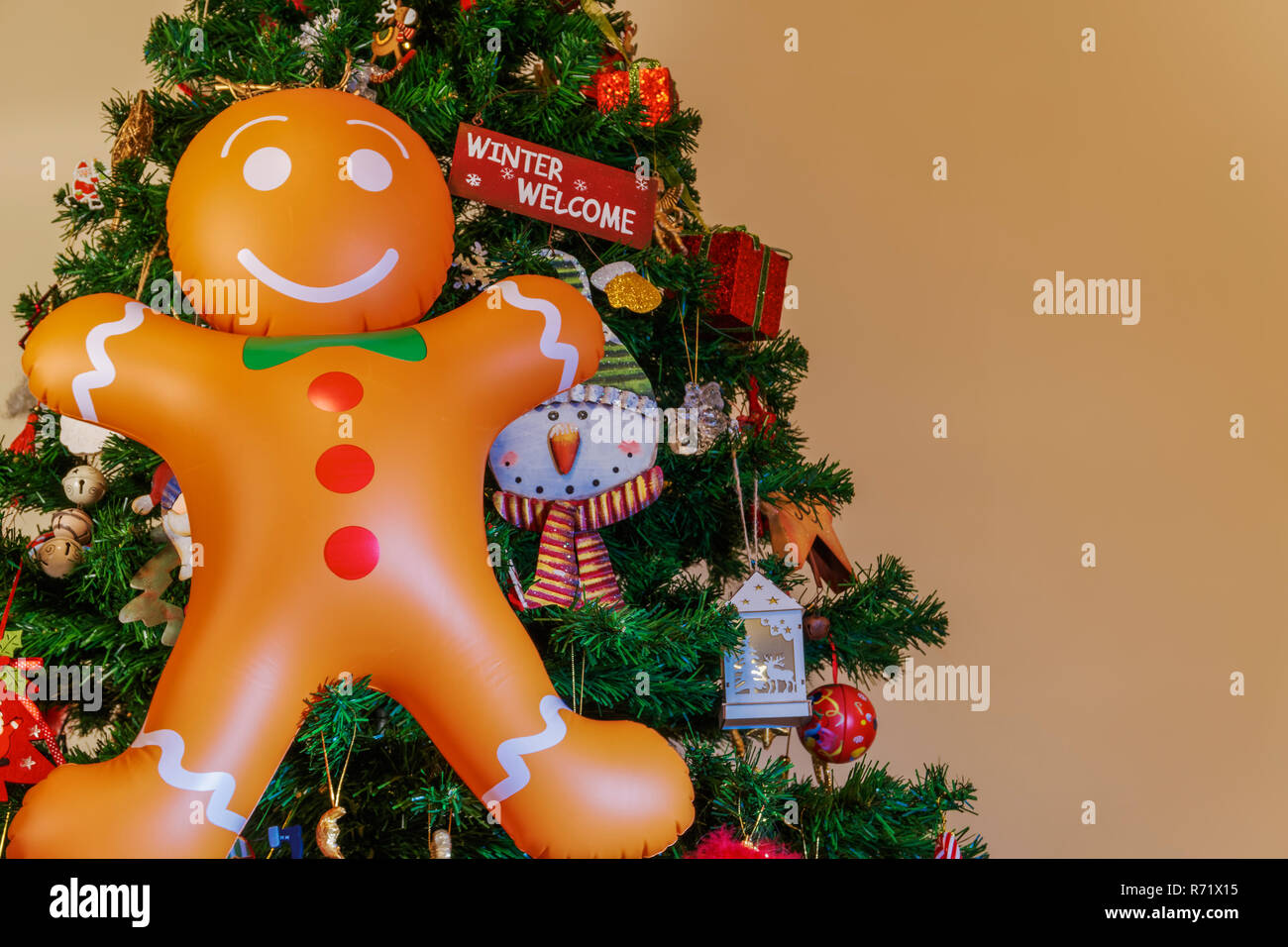 Große aufblasbare Gingerbread Man mit copy Speicherplatz auf einen Weihnachtsbaum. Luft ausgeblasen saisonale Abbildung hängende vor einem künstlichen Weihnachtsbaum. Stockfoto