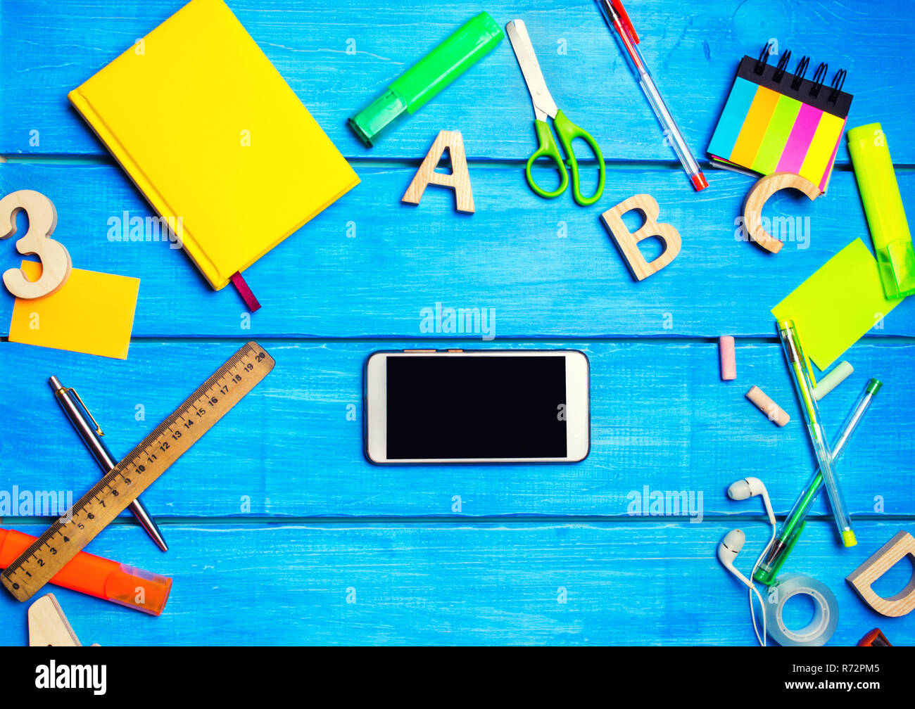 Schulsachen in der Schule Schreibtisch mit Telefon im Zentrum,  Schreibwaren, Bürobedarf, Schule Konzept, blauen Hintergrund, kreatives  Chaos, Marker, Stifte, Notizblöcke, s Stockfotografie - Alamy