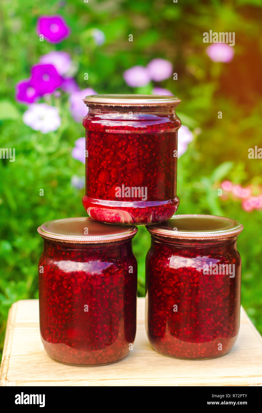 Banken mit duftenden hausgemachte Himbeermarmelade im Garten. Im Sommer Ernte. süße Speisen. Lebensmittel Vorrat für den Winter. Landschaft Natur, Outdoor. Stockfoto