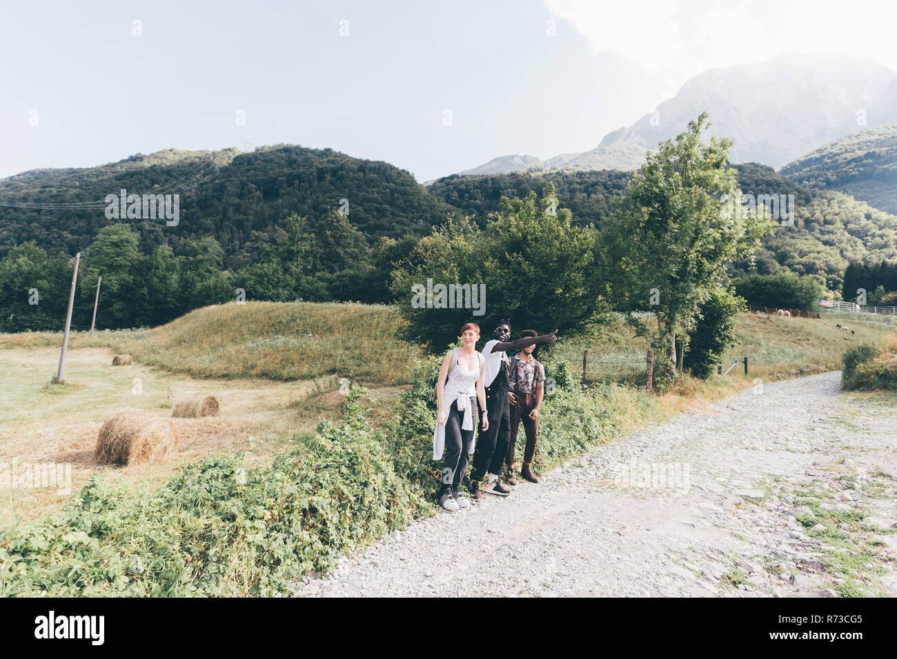 Jungen Erwachsenen Wanderer Freunde durchblättern heben auf den ländlichen Feldweg, Primaluna, Trentino-Südtirol, Italien Stockfoto
