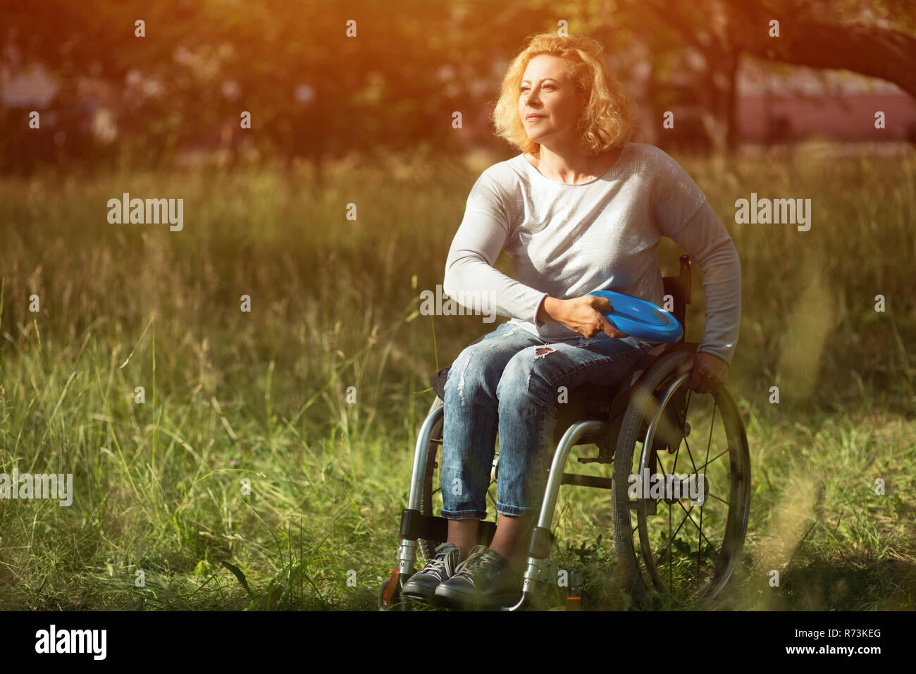 Frau im Rollstuhl wirft Frisbee Stockfoto