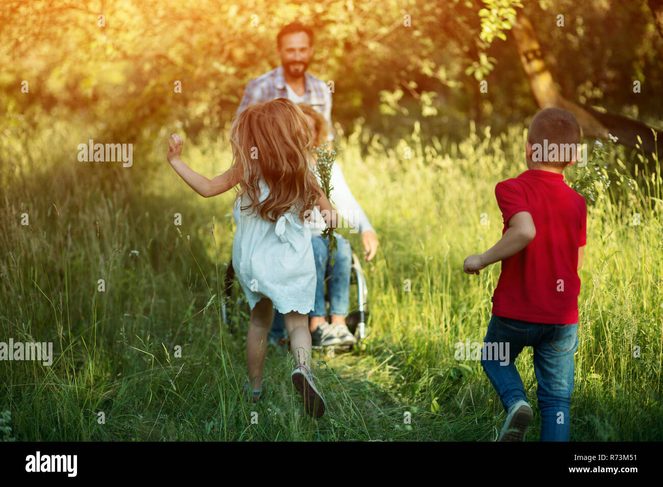 Kinder laufen für ihre behinderte Mutter im Park Stockfoto