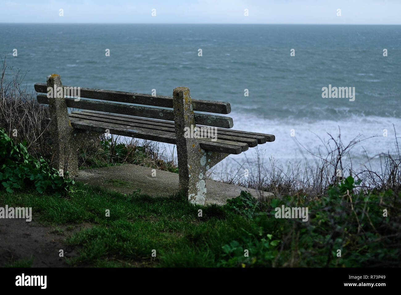 Einen leeren Sitz, Sitzbank, mit Blick aufs Meer auf einem kalten Wintertag in Cornwall​, UK. Stockfoto