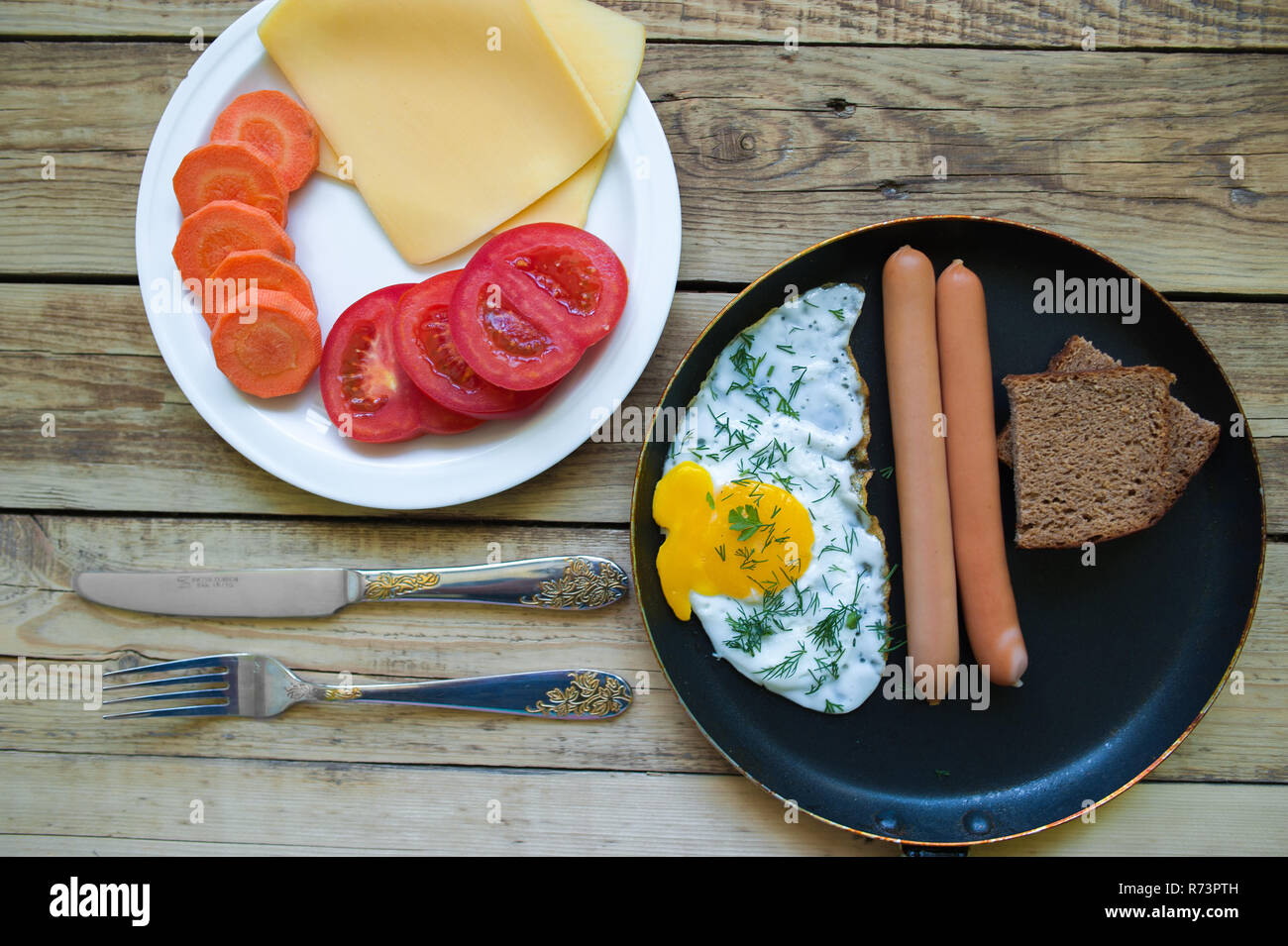 Köstliches Frühstück mit Rührei, Würstchen, Karotten, Käse, Brot und ...