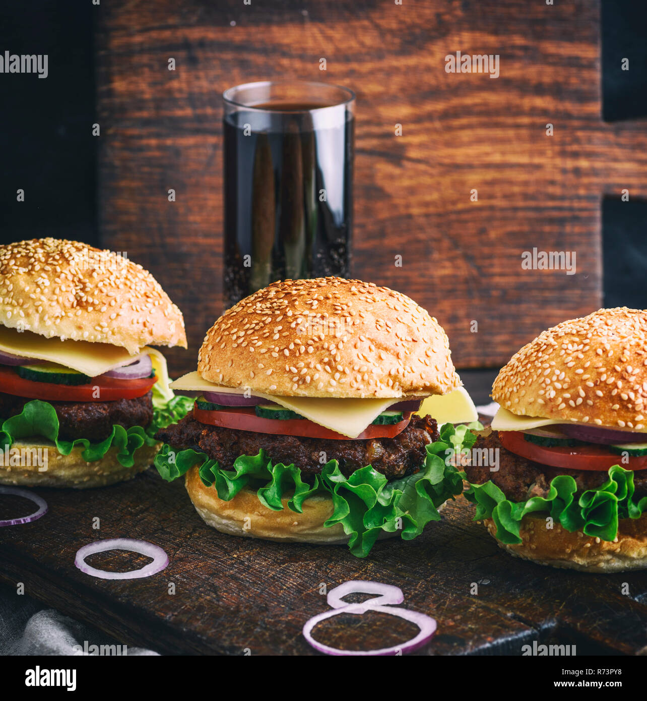 Hamburger mit Rindfleisch, Zwiebeln, Tomaten, Salat, Käse und Gewürze Stockfoto