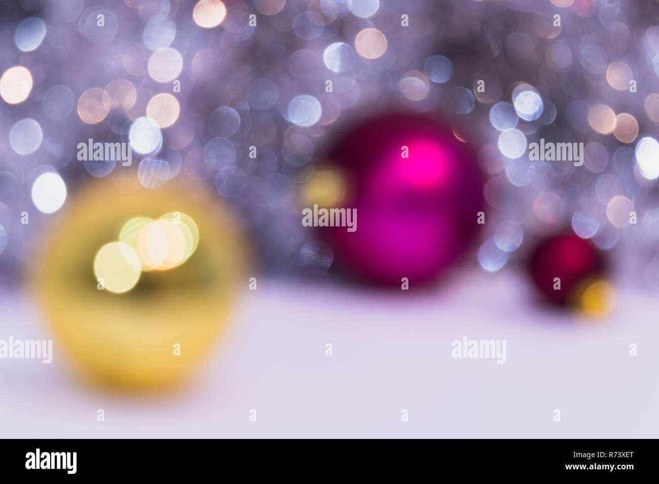 Blurry Christmas background mit Weihnachtskugeln und Bokeh. Drei XMAS Kugeln Gold und Pink. Neues Jahr Feier Stockfoto