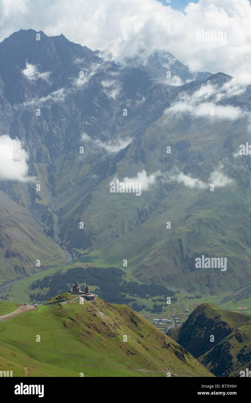 Die gergeti Trinity Kirche hoch auf den Hügeln mit Blick auf das Dorf von Gergeti, Georgia. Name der Orthodoxen Kirche ist die Kirche der Heiligen Dreifaltigkeit Stockfoto