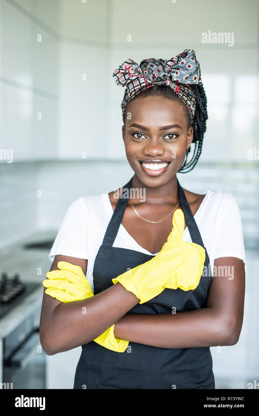 Junge afrikanische Frau in gelb Handschuhe, die Daumen zeigen oben im Zimmer Stockfoto