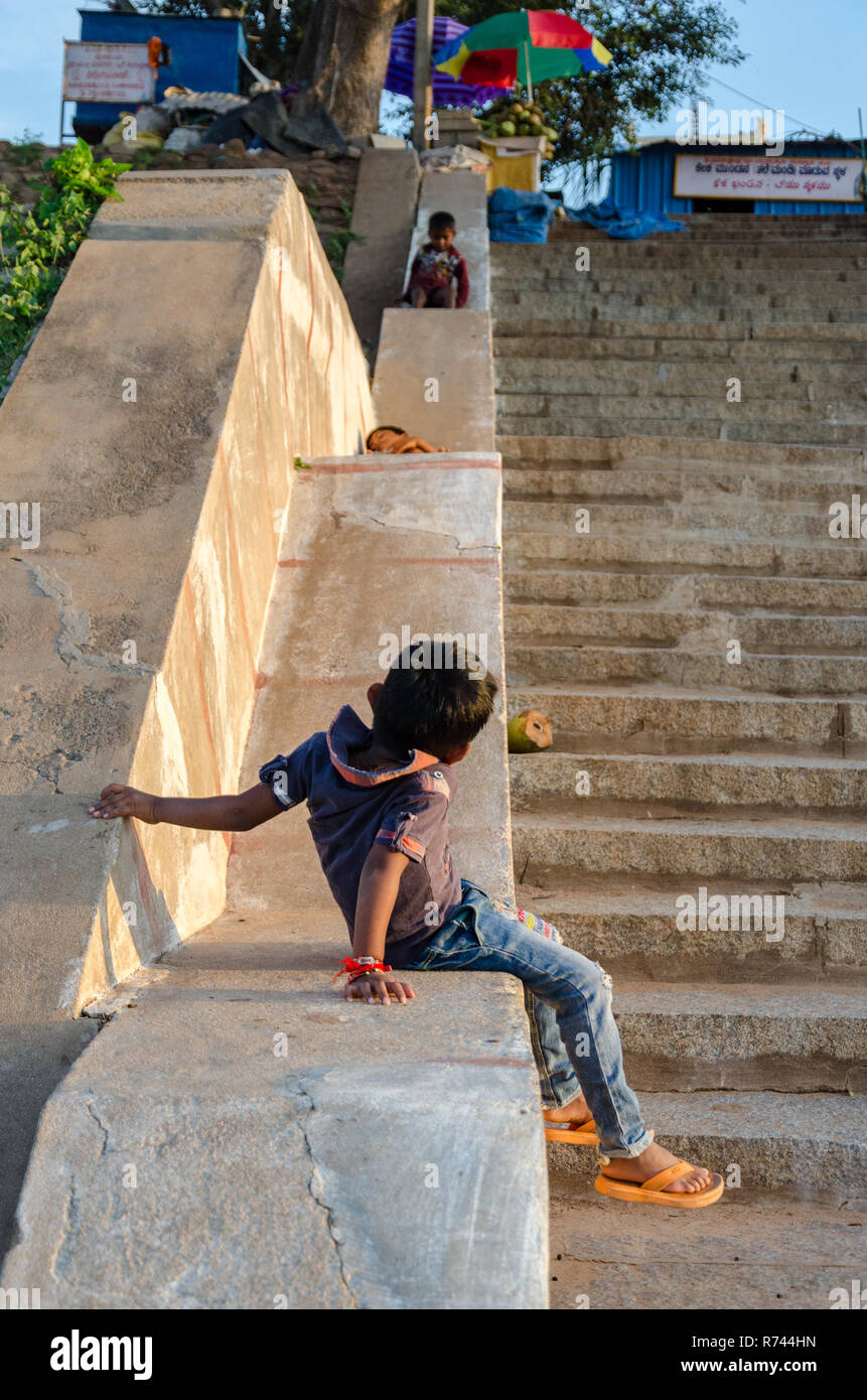 Drei junge indische Kinder spielen auf einem Zement Treppe Geländer, rutschen. Stockfoto