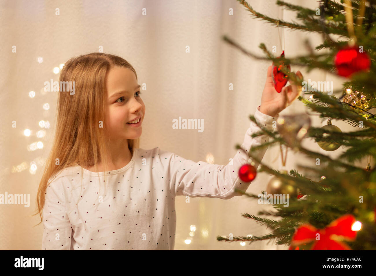 Glückliches Mädchen im roten Kleid Dekoration Weihnachtsbaum Stockfoto