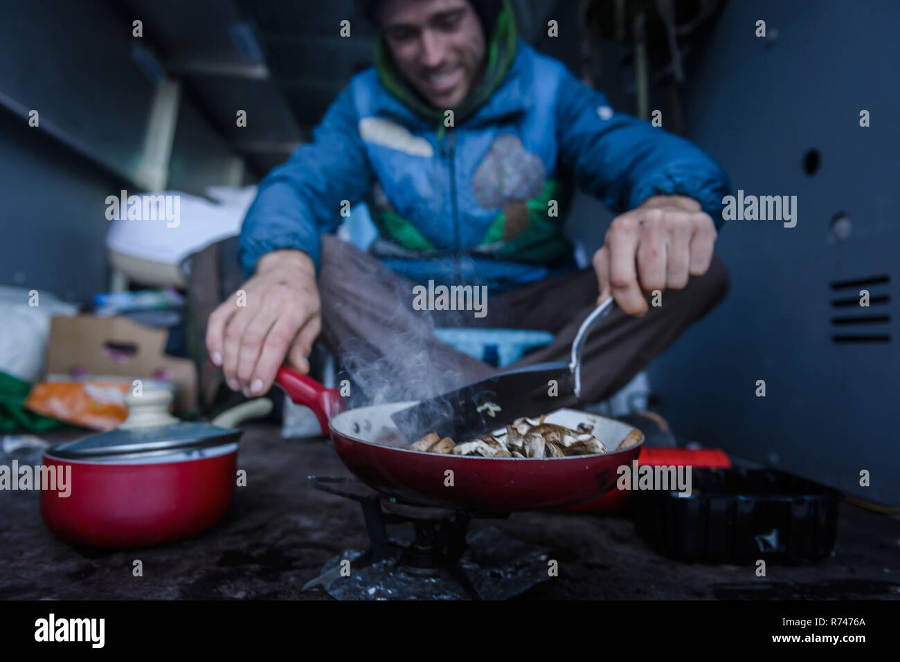 Junge männliche Kletterer kochen Frühstück im Wohnmobil Stockfoto