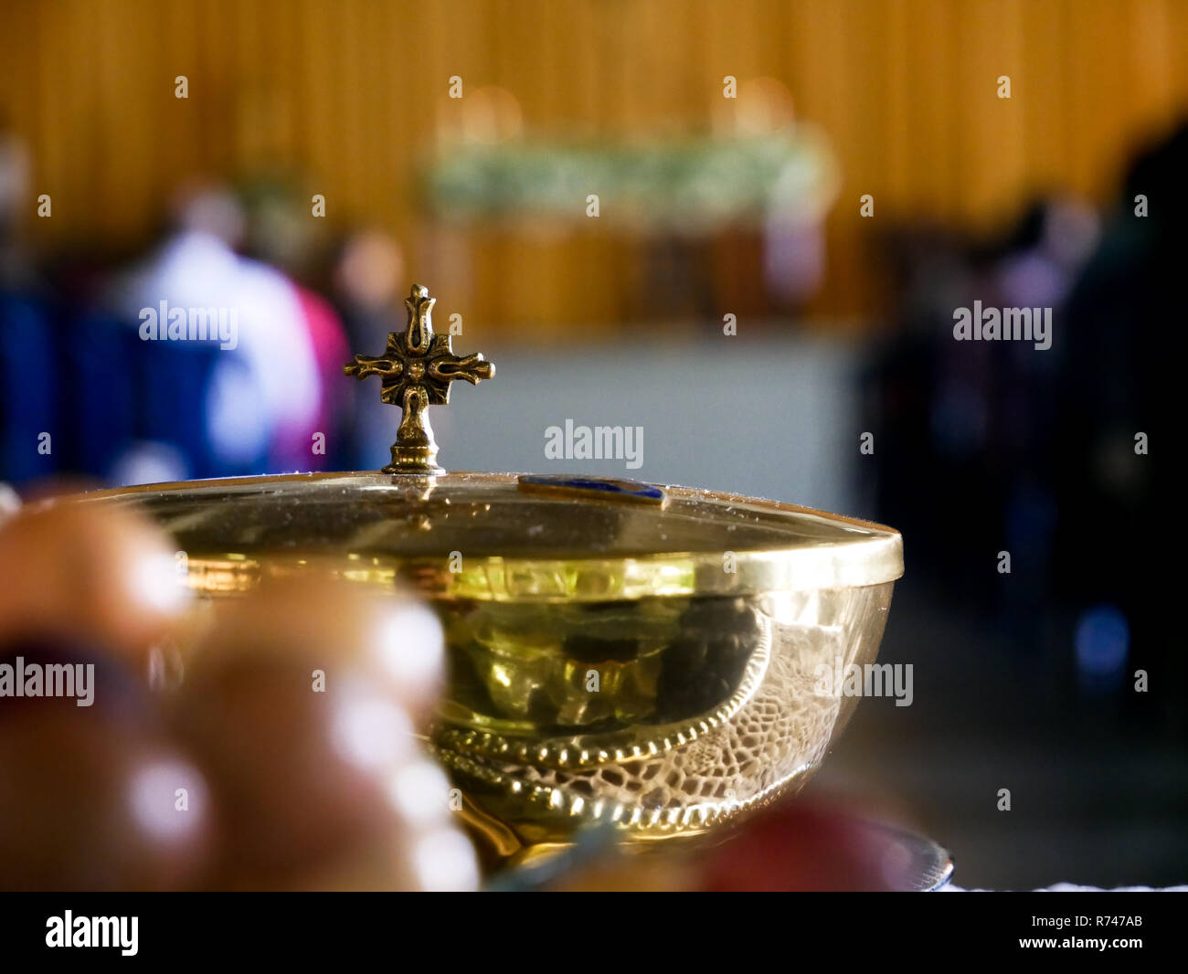 Golden copon mit einem Kreuz als Angebot vor katholische Messe unscharfen Hintergrund und Trauben im Vordergrund Stockfoto