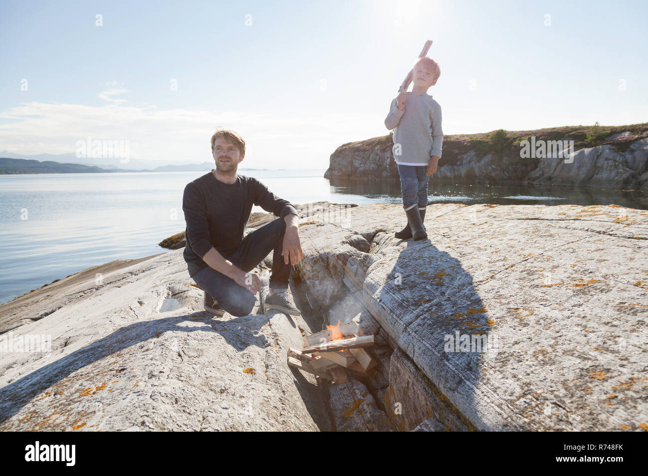 Junge und Vater von Lagerfeuer auf Einlass rock, Aure, Mehr og Romsdal, Norwegen Stockfoto