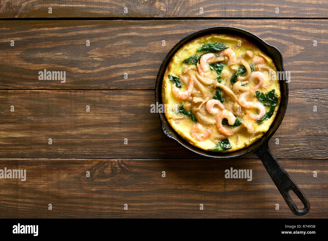 Pilze und Spinat frittata mit Garnelen in einer Pfanne auf hölzernen Hintergrund mit kopieren. Ansicht von oben, flach Stockfoto