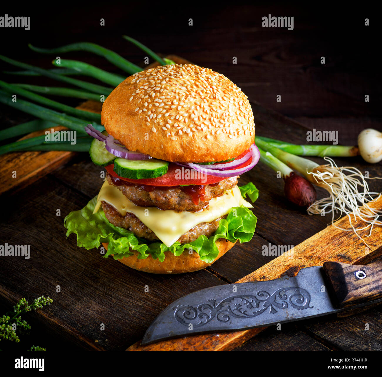 Double Cheeseburger mit Gemüse und Käse, weiße runde Brötchen Mit Sesam Stockfoto