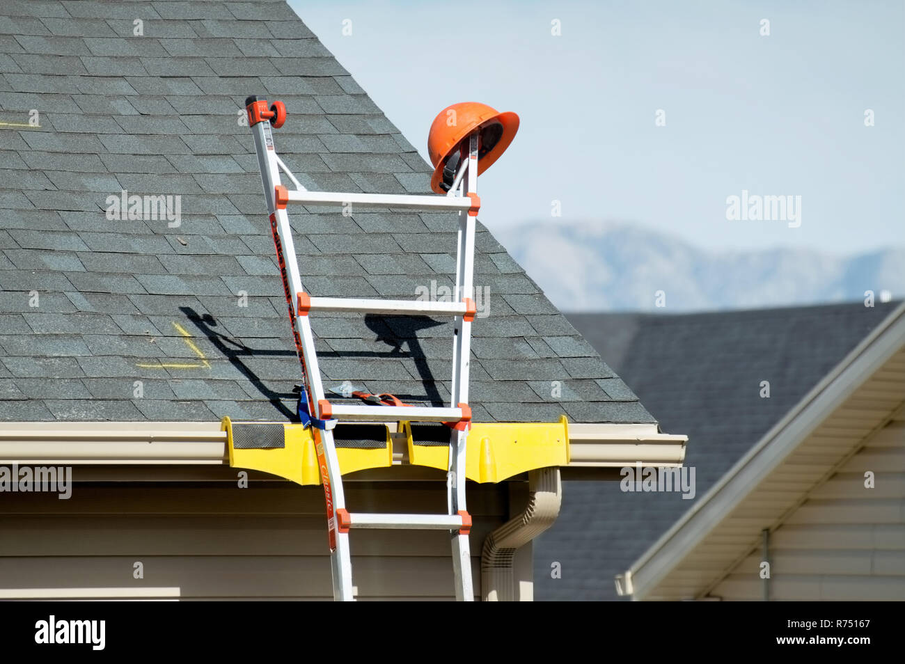 Einen harten Hut sitzen auf der obersten Sprosse einer Leiter. Stockfoto