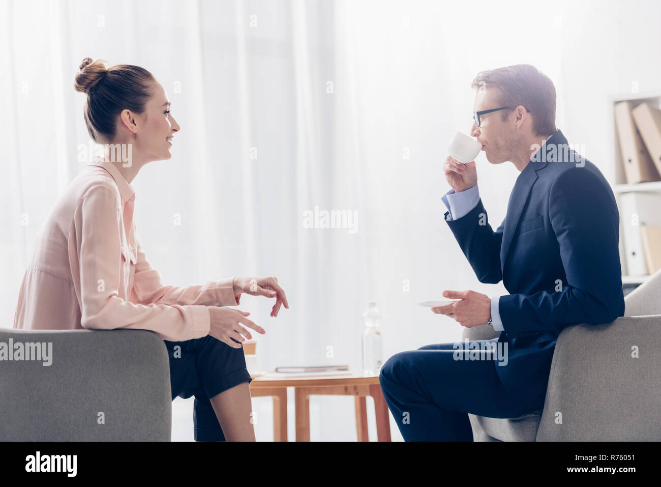 Seitenansicht des stattlichen Kaffee trinken, lächelnd Journalistin bei ihm im Büro Stockfoto