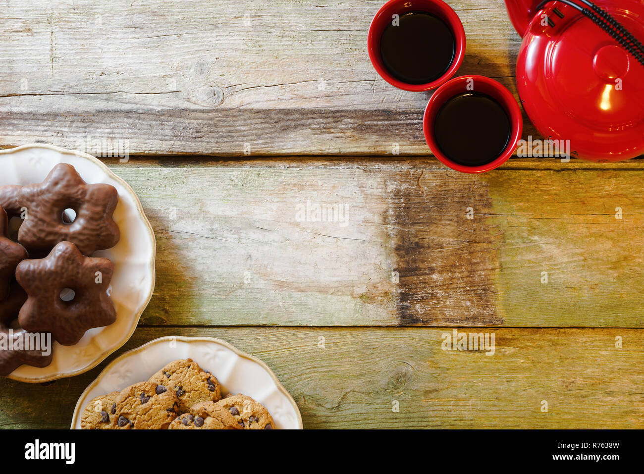 Flach der rustikalen Holztisch mit Chocolate Chip Cookies in keramischen Platten, rote Teekanne und Tassen. Mit kopieren. Stockfoto