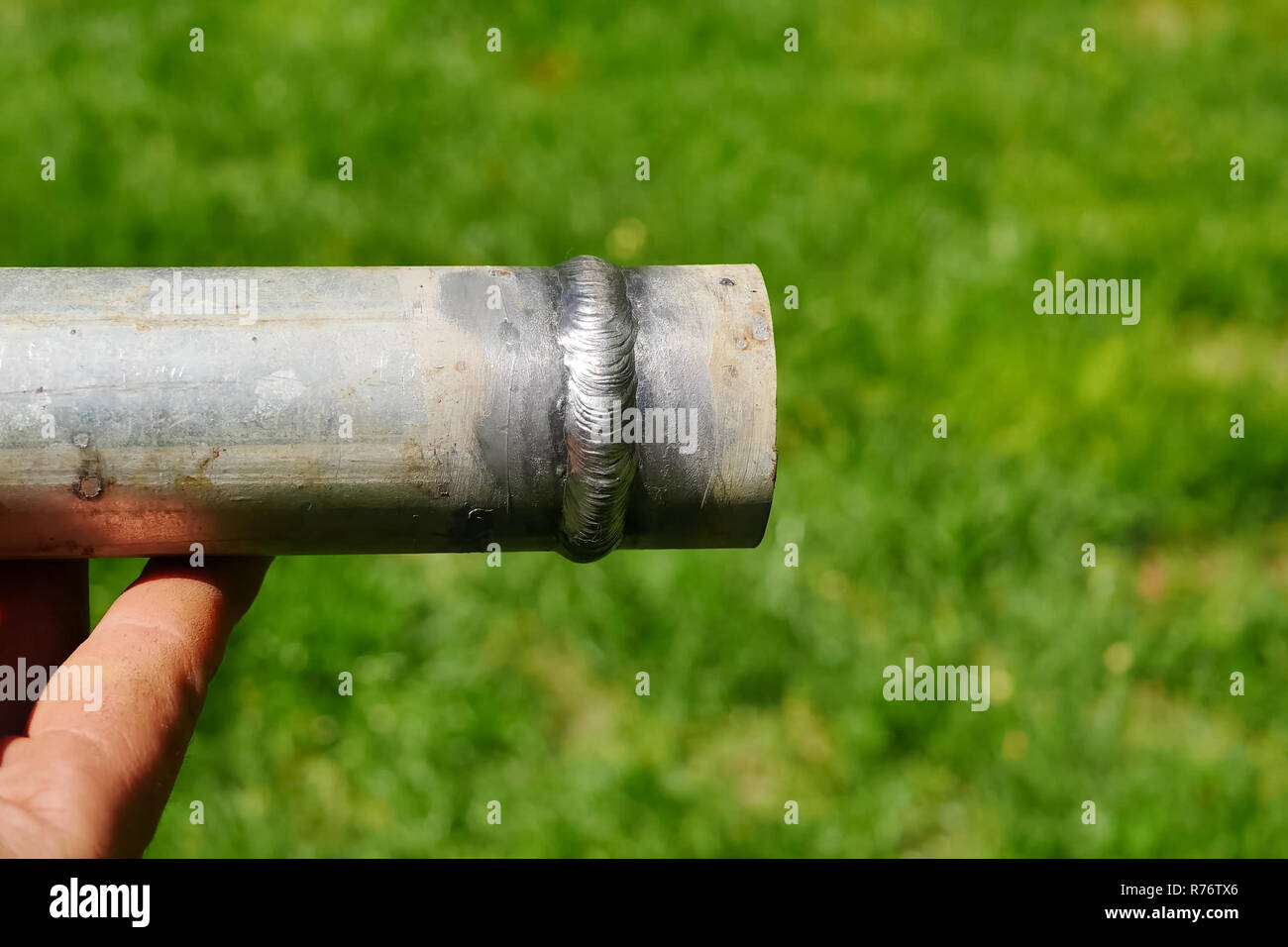 Metallrohr mit einer Schweißnaht in der Hand des Menschen des Schweißers. Stockfoto