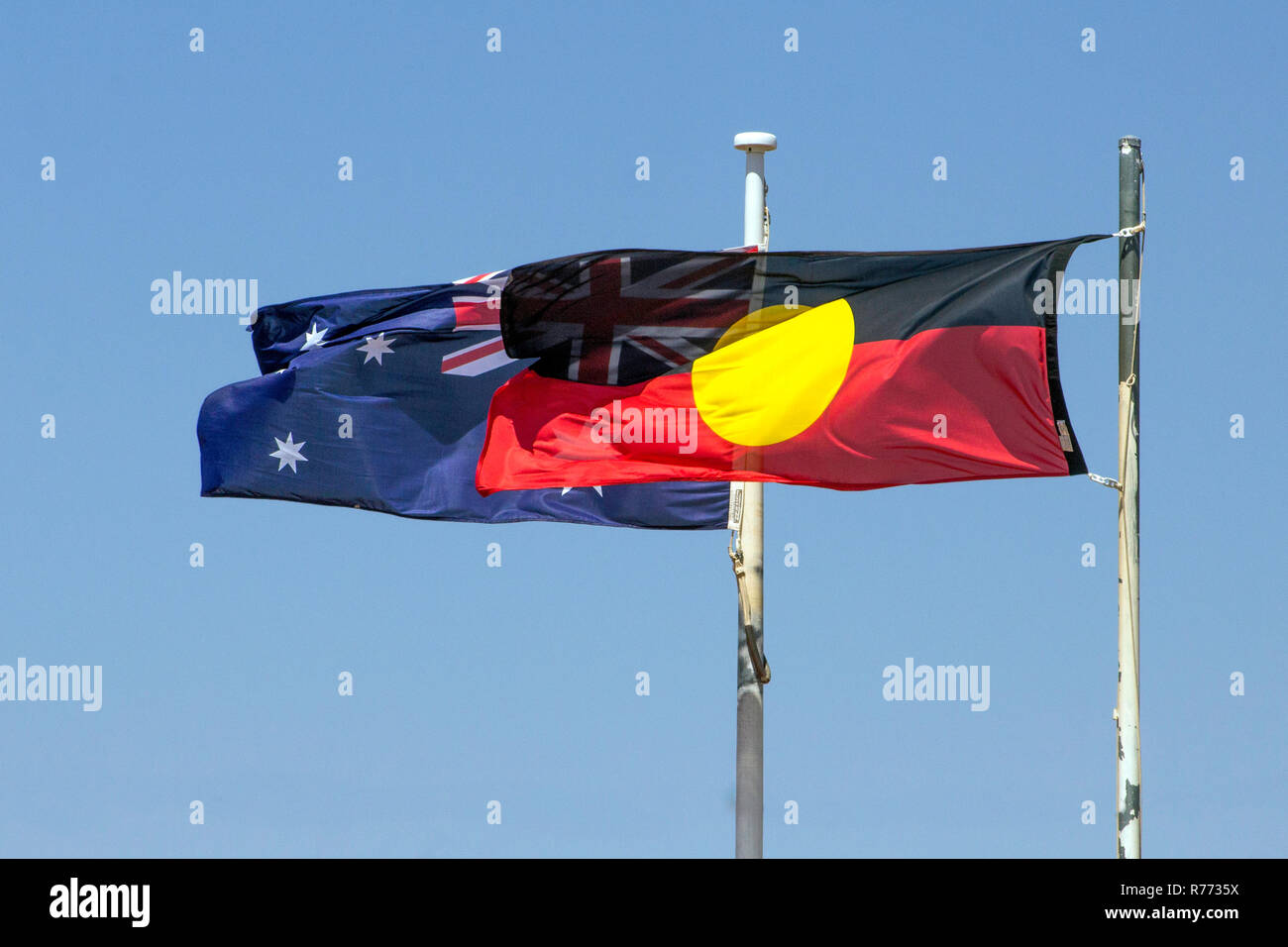 Australische Aborigines Flaggen im Wind, mit Union Jack durch die darüber liegende Aboriginal Flagge sichtbar Stockfoto