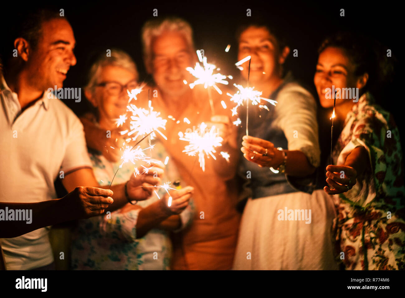Gruppe von Menschen viel Spaß feiern gemeinsam Silvester oder zum Geburtstag mit funkelt Licht und Feuerwerk in Freundschaft im Freien am Abend Zeit - Famil Stockfoto