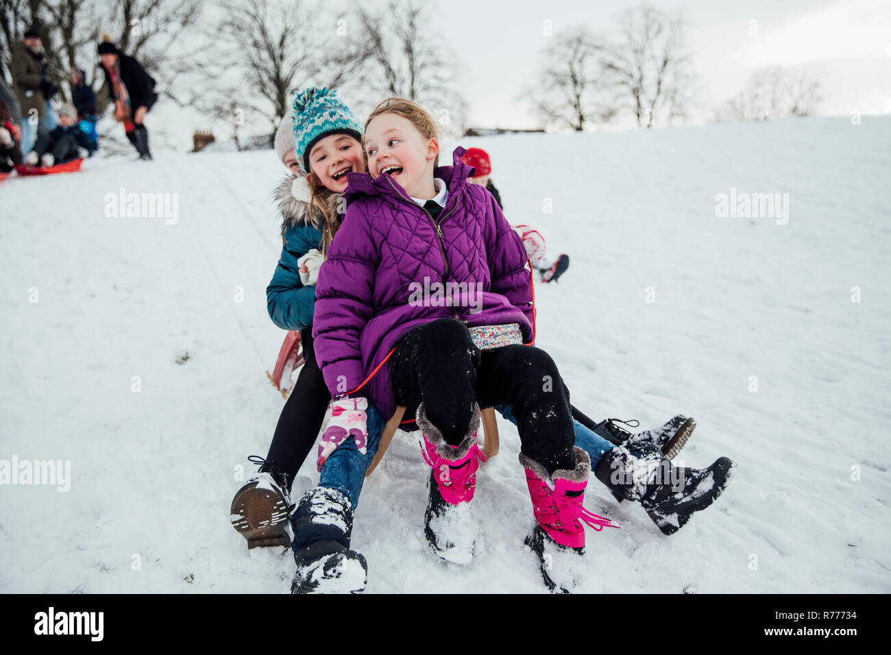 Mädchen Racing auf Schlitten im Schnee Stockfoto