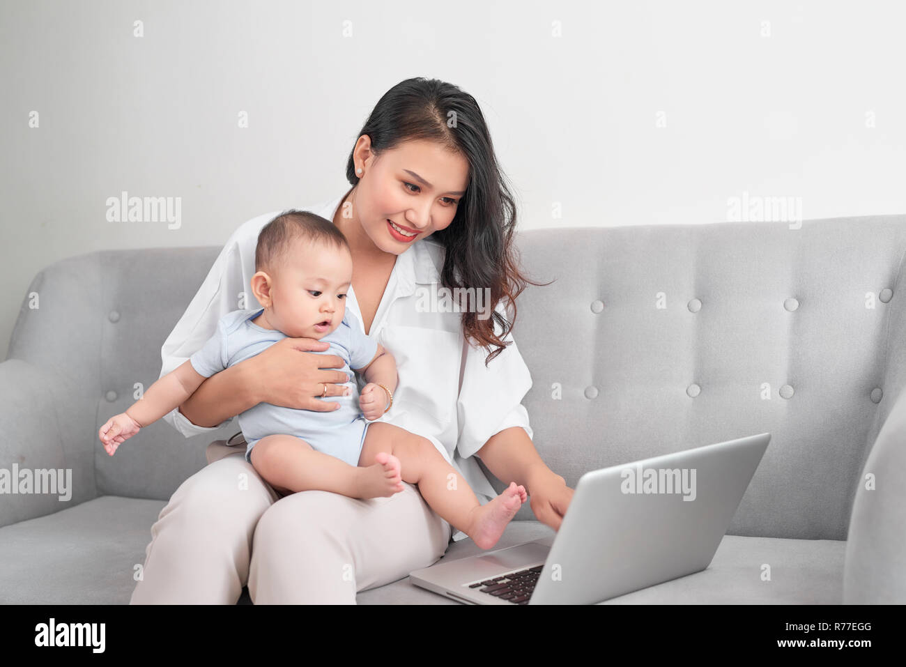 Junge Mutter mit Baby während der Arbeit im Home Office Stockfoto