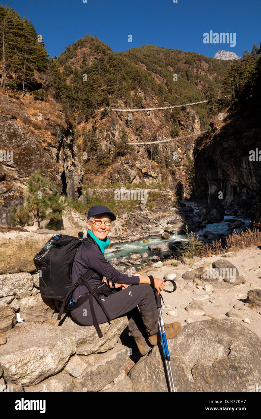 Nepal, Larja Dobhan, Senior weibliche Touristen auf dem Everest Base Camp Trek, ruht neben Dudh Khosi Fluss am oberen und unteren Larja Brücken Stockfoto