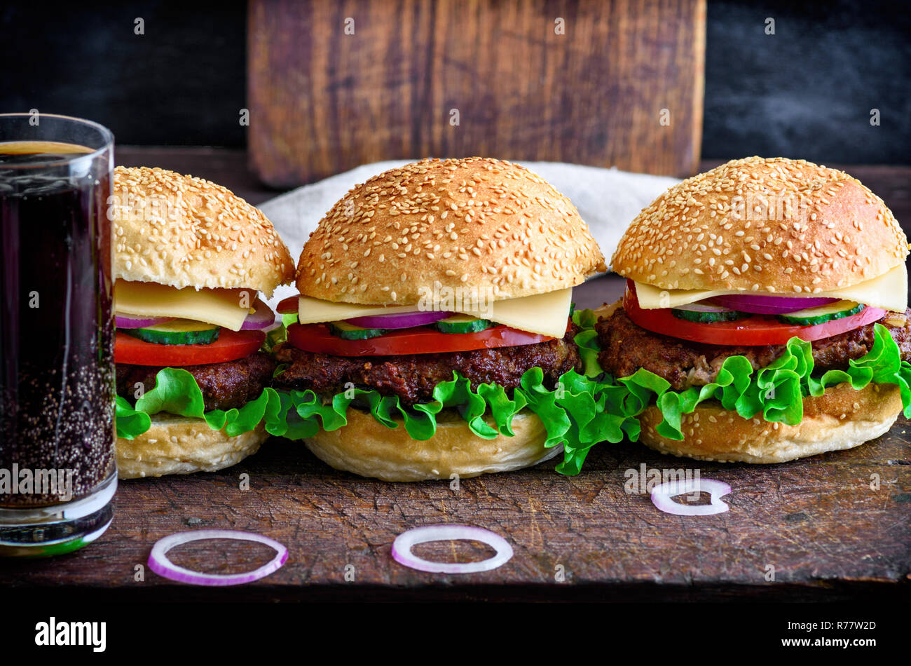 Hamburger mit Rindfleisch, Zwiebeln, Tomaten, Salat, Käse und Gewürze Stockfoto