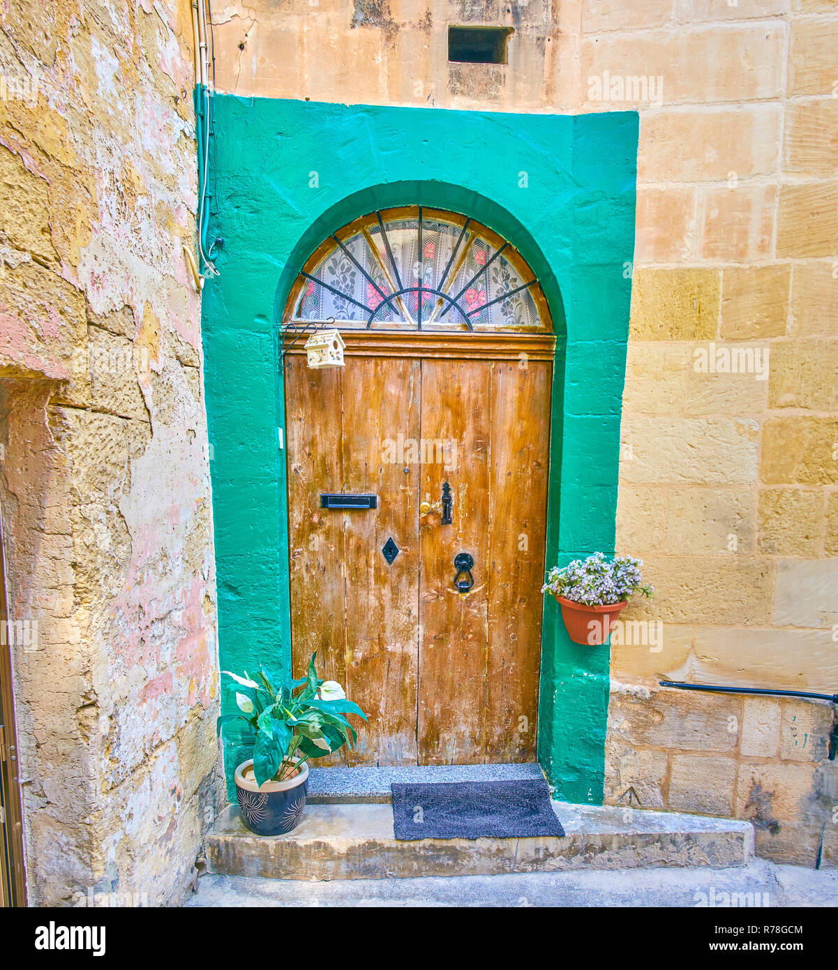 Die alte Tür mit der halben Runde Fenster oben und Blumen in Töpfe könnte  in der Altstadt von Mosta, Malta gefunden werden Stockfotografie - Alamy