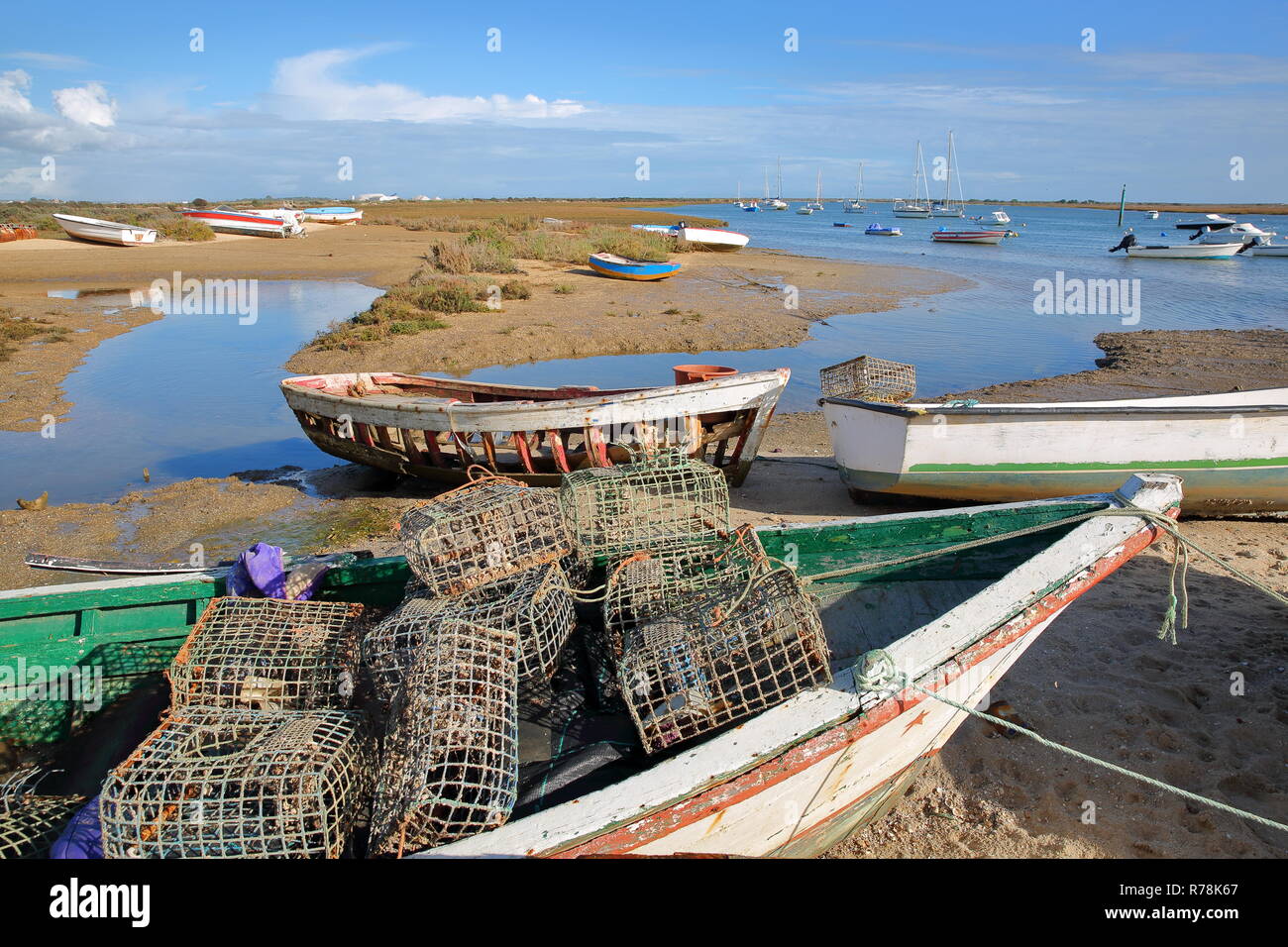 Bunte Fischerboote am Strand von Santa Luzia, einem Fischerhafen in der Nähe von Tavira, Algarve, Portugal, mit Angeln Körbe im Vordergrund. Stockfoto