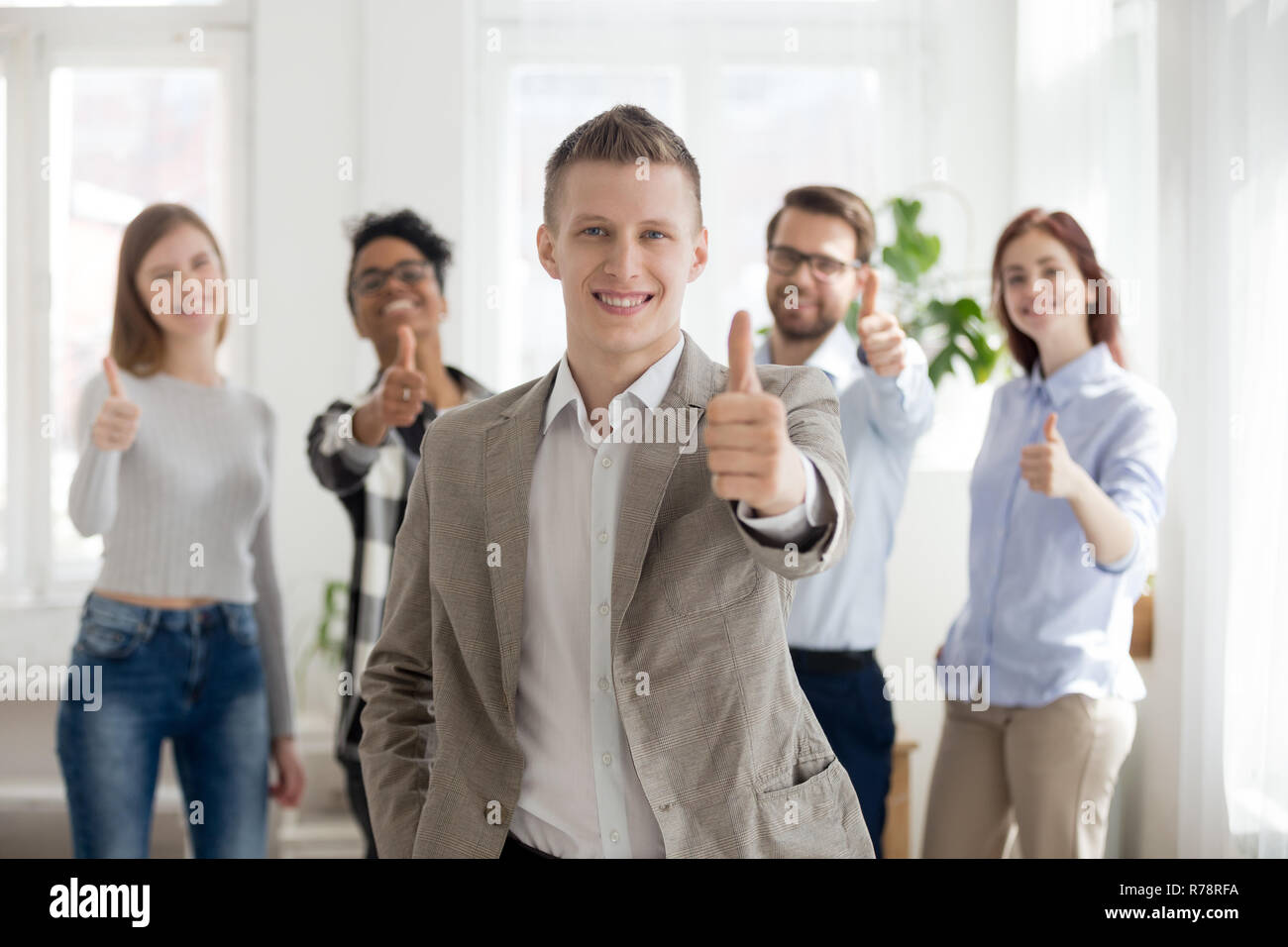 Lächelnd männliche Mitarbeiter mit vielfältigen Team zeigen Daumen hoch Stockfoto
