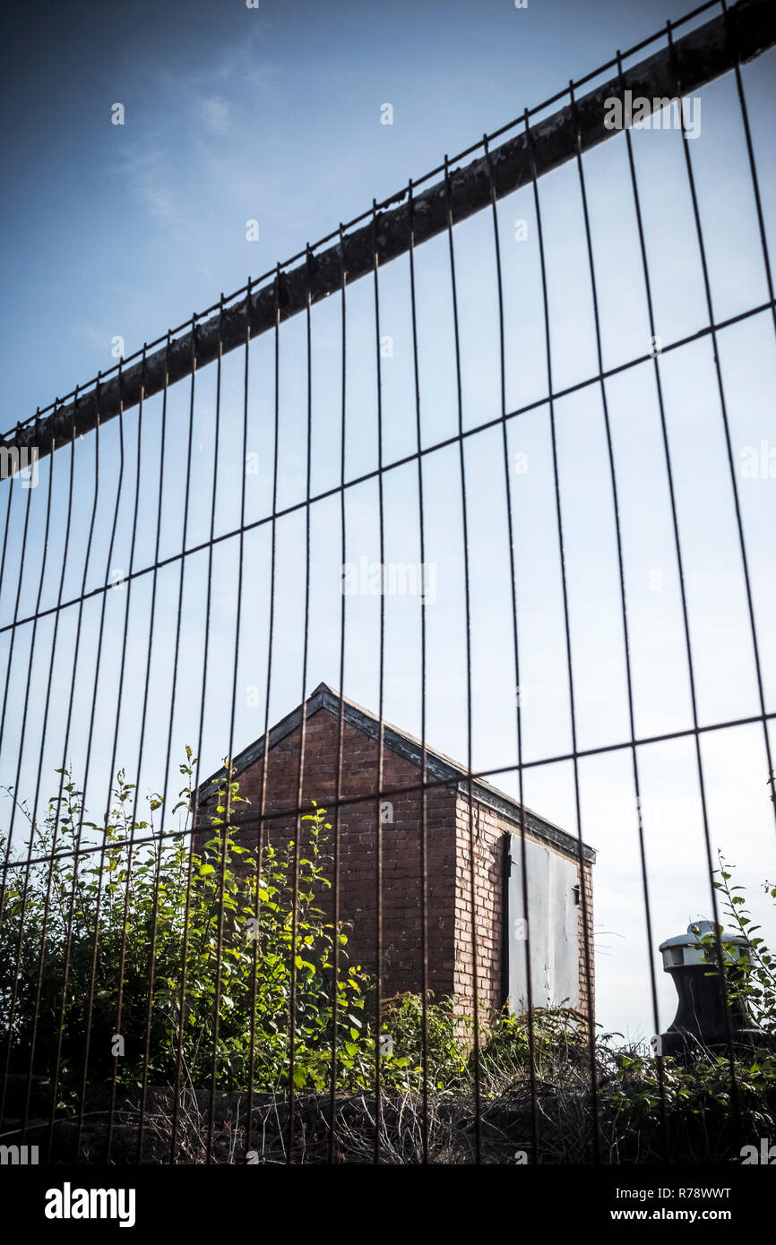 Kleine verlassene Steingebäude, shack isoliert oder Schuppen, hinter einer temporären Zaun Stockfoto