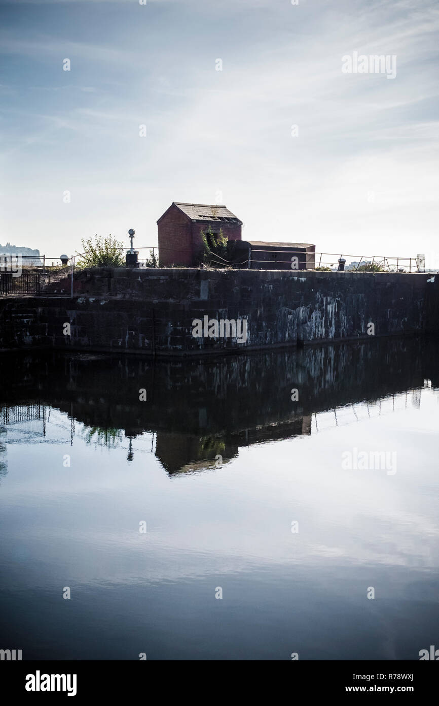 Kleine verlassene Steingebäude, Hütte oder Schuppen, auf einem Hafen oder Dock in den ruhigen Wasser wider. Stockfoto