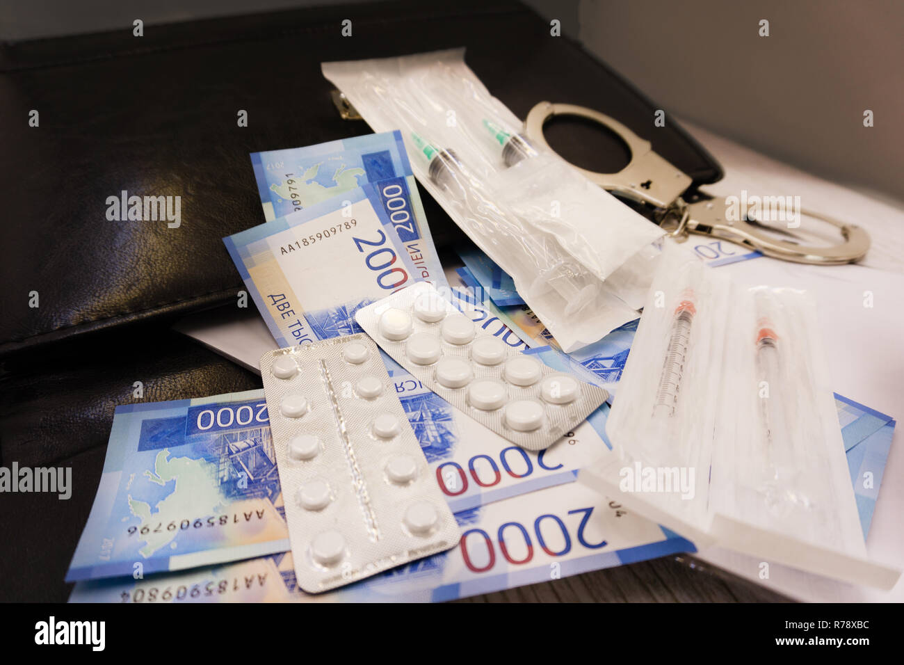 Handschellen und Pillen und Drogen auf hölzernen Tisch Stockfoto