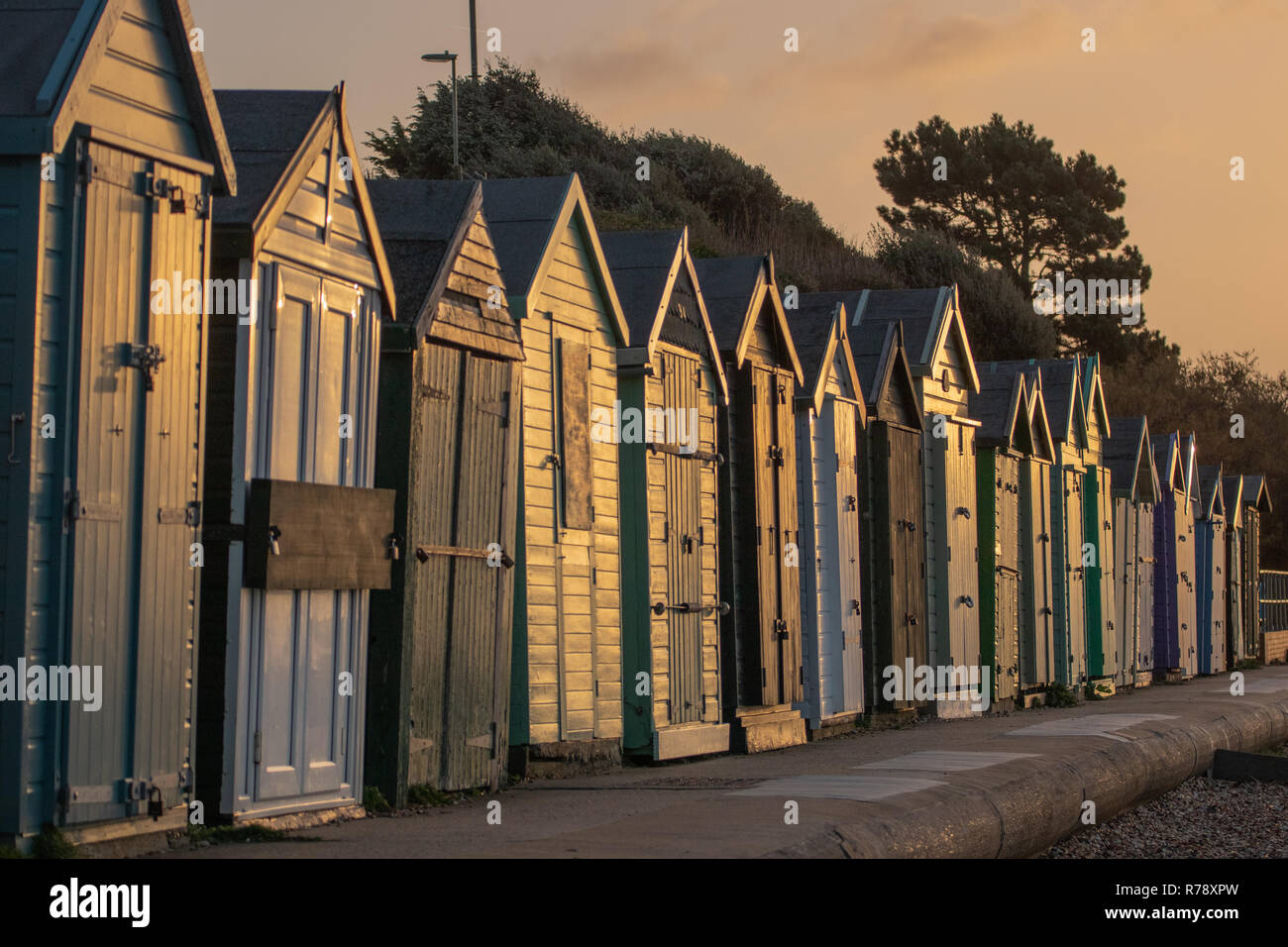 Eine Reihe von grünen Strand Hütten mit der frühen Morgensonne auf der Vorderseite ein warmes Licht. Stockfoto