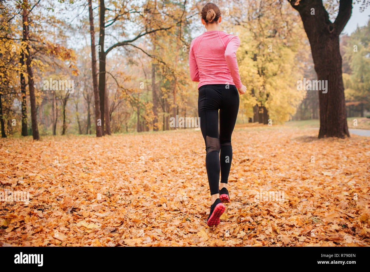 Bild der jungen Frau im Park läuft. Es ist kühles Wetter draußen. Orange Blätter liegen auf dem Boden. Junge Frau joggen. Sie laufen allein. Stockfoto