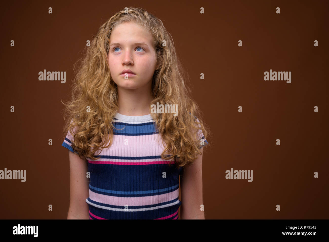 Junge schöne Blonde Mädchen im Teenageralter Denken gegen braunen Hintergrund Stockfoto