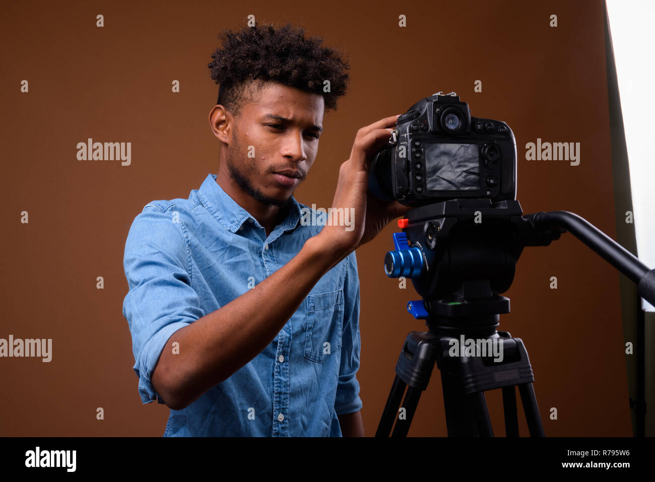Junge schöne afrikanischer Mann vlogging mit DSLR-Kamera im Studio Stockfoto