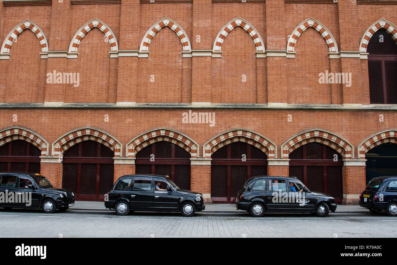 Profil aus einer Reihe von schwarzen Taxis oder Taxis auf einer Londoner Straße vor einer Stadt Gebäude mit Kopie Raum Stockfoto