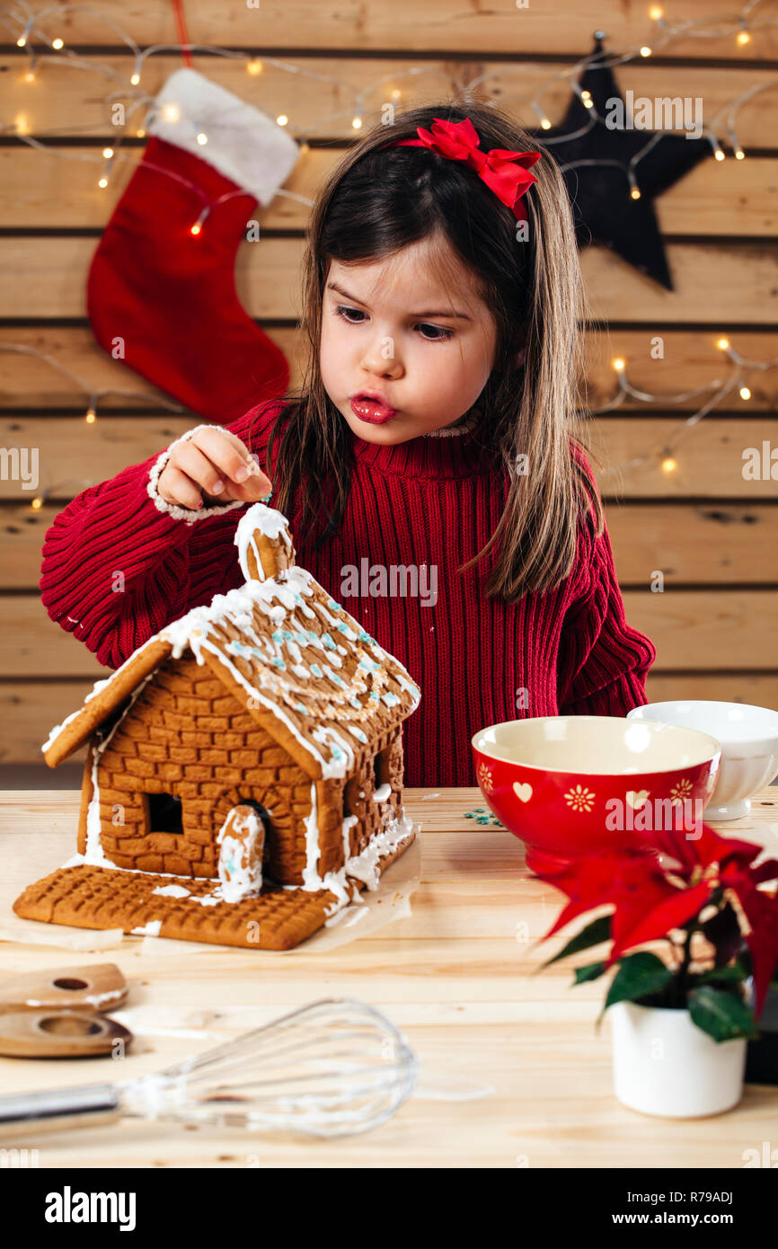 Foto eines jungen Mädchens Dekorieren ein Lebkuchenhaus zu Hause kurz vor Weihnachten. Stockfoto