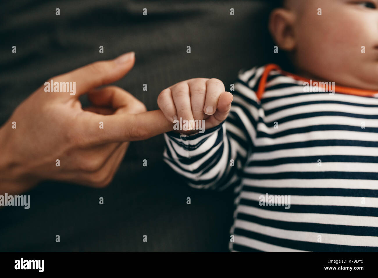 Baby halten Sie die Finger seiner Mutter schlafen im Bett. Baby sicher fühlen, indem Sie einen Finger seiner Mutter. Stockfoto