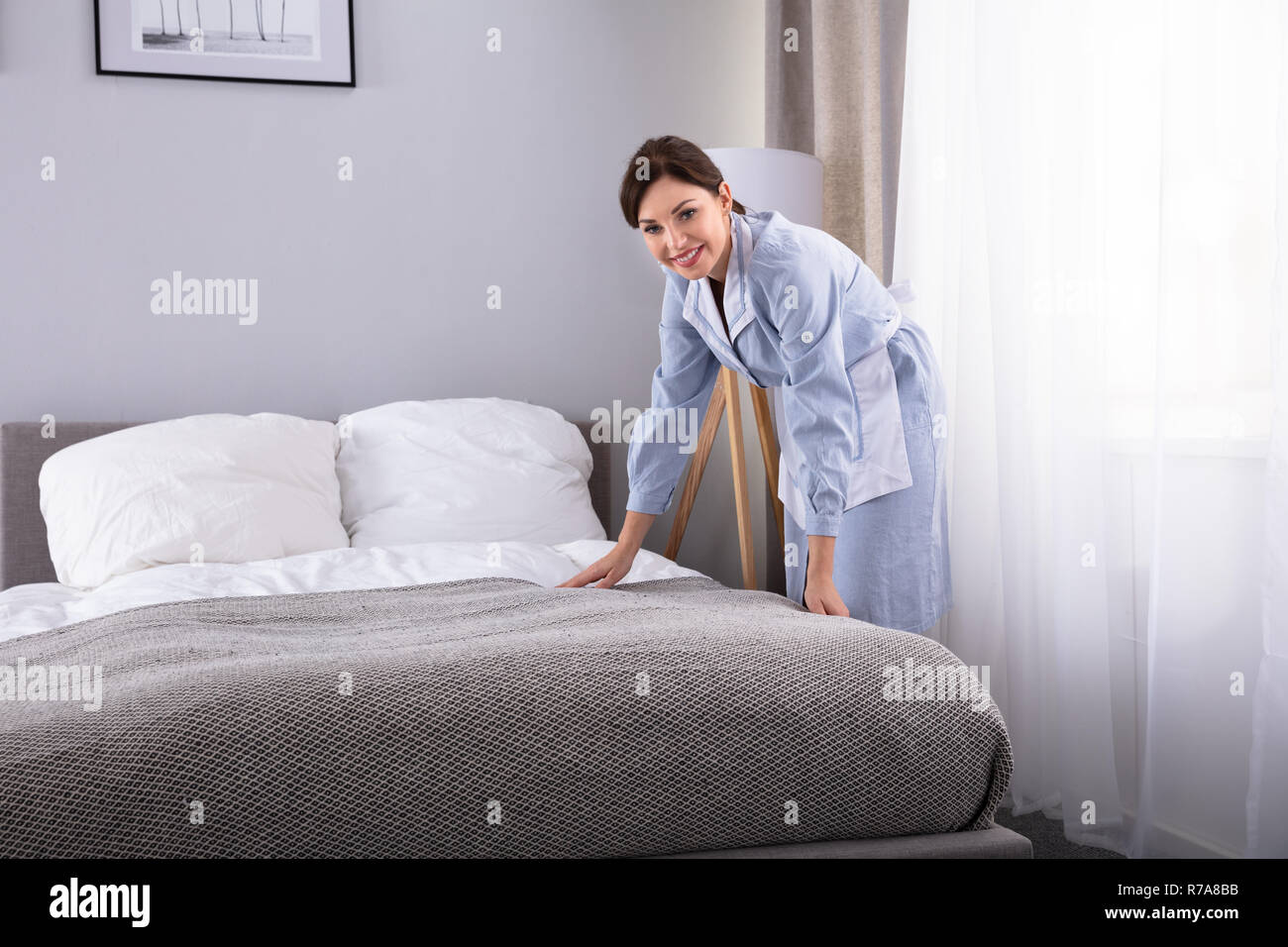 Lächelnd weibliche Haushälterin, Bett im Hotelzimmer Stockfoto